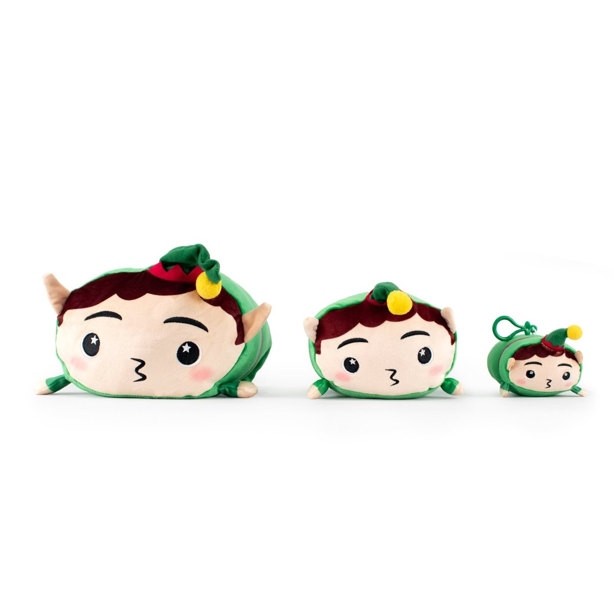 Three Jingle the Elf Plushies, each a different size, are lined up from largest to smallest. All feature green hats with yellow pom-poms, brown hair, and cute faces. The perfect Christmas plushie set! White background.