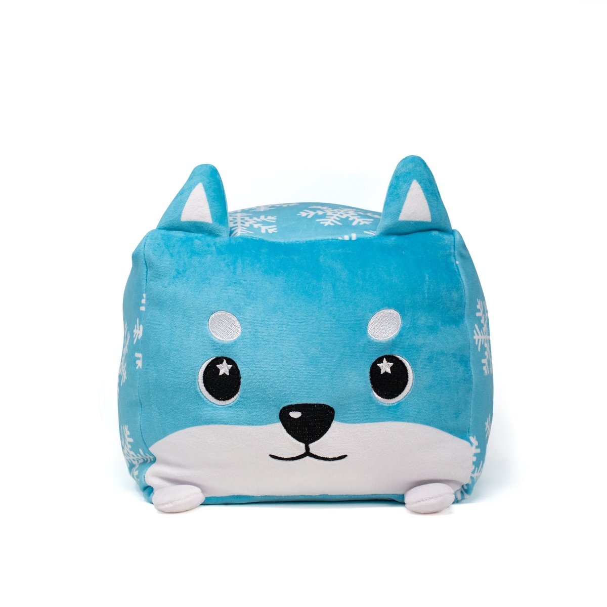The Frost Plushie is a blue, square holiday pillow with white snowflake patterns, a cute cartoon face, upright ears, and small white feet—just like a Moosh-Moosh Squared2.