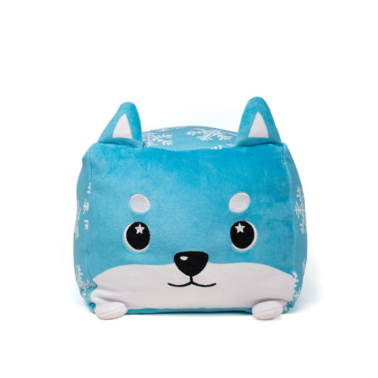 The Frost Plushie is a blue, square holiday pillow with white snowflake patterns, a cute cartoon face, upright ears, and small white feet—just like a Moosh-Moosh Squared2.