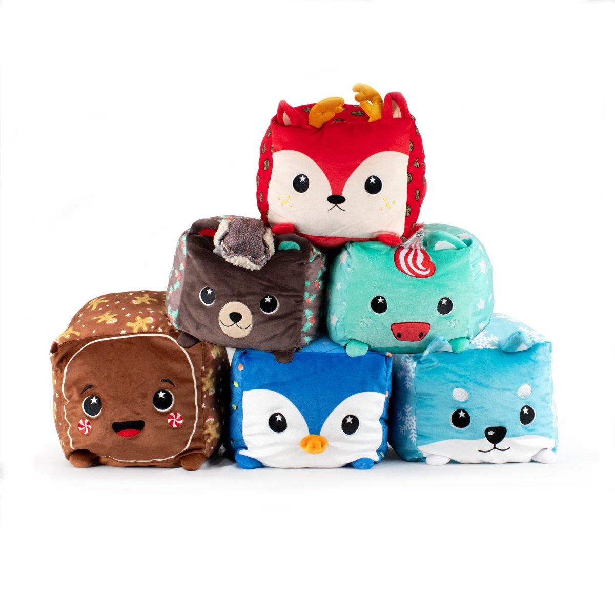 Six Belle Plushie Squared2 holiday cube toys with animal faces and bright colors are stacked pyramid-style, featuring a plush reindeer, deer, unicorn, penguin, fox, and a brown animal with antlers.