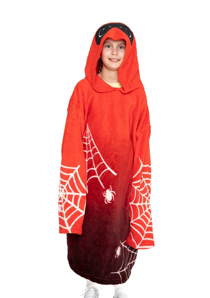 A child smiling and standing against a white background, wearing the Muffet the Spider Hooded Blanket featuring spiderweb and spider designs.