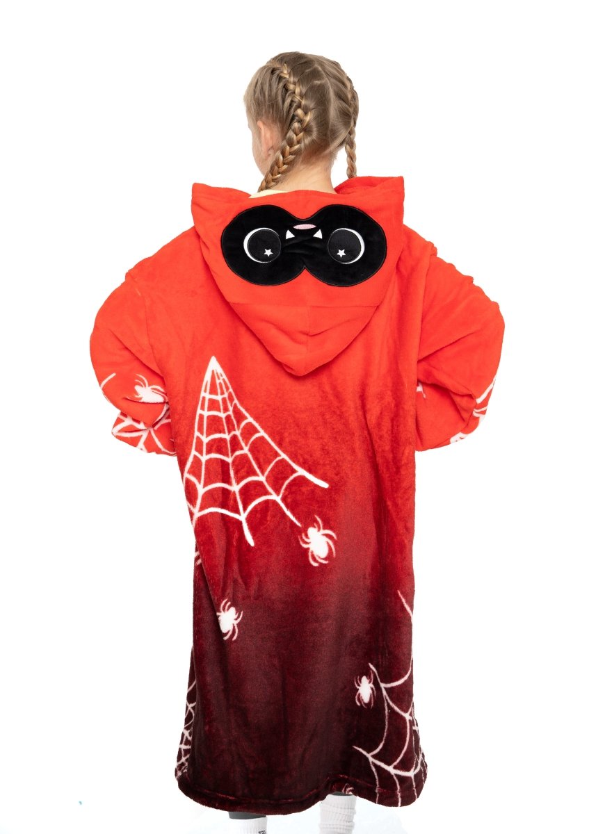 A child with braided hair wears the Muffet the Spider Hooded Blanket, a red robe with white spiderwebs, cartoon eyes on the hood, and spiders. Cozy and fun for Halloween, the child faces away from the camera.