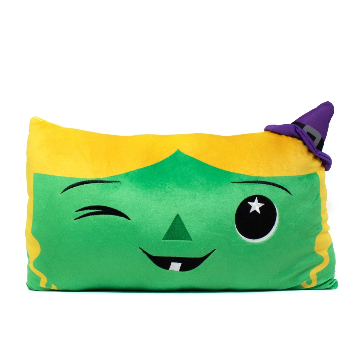 The "Marnie the Witch Pillow" is a rectangular, green, and plush cushion resembling a stuffed animal. It features a cartoon witch face with a winking eye, triangular nose, small fang, yellow hair section, and a purple witch hat in the top right corner.