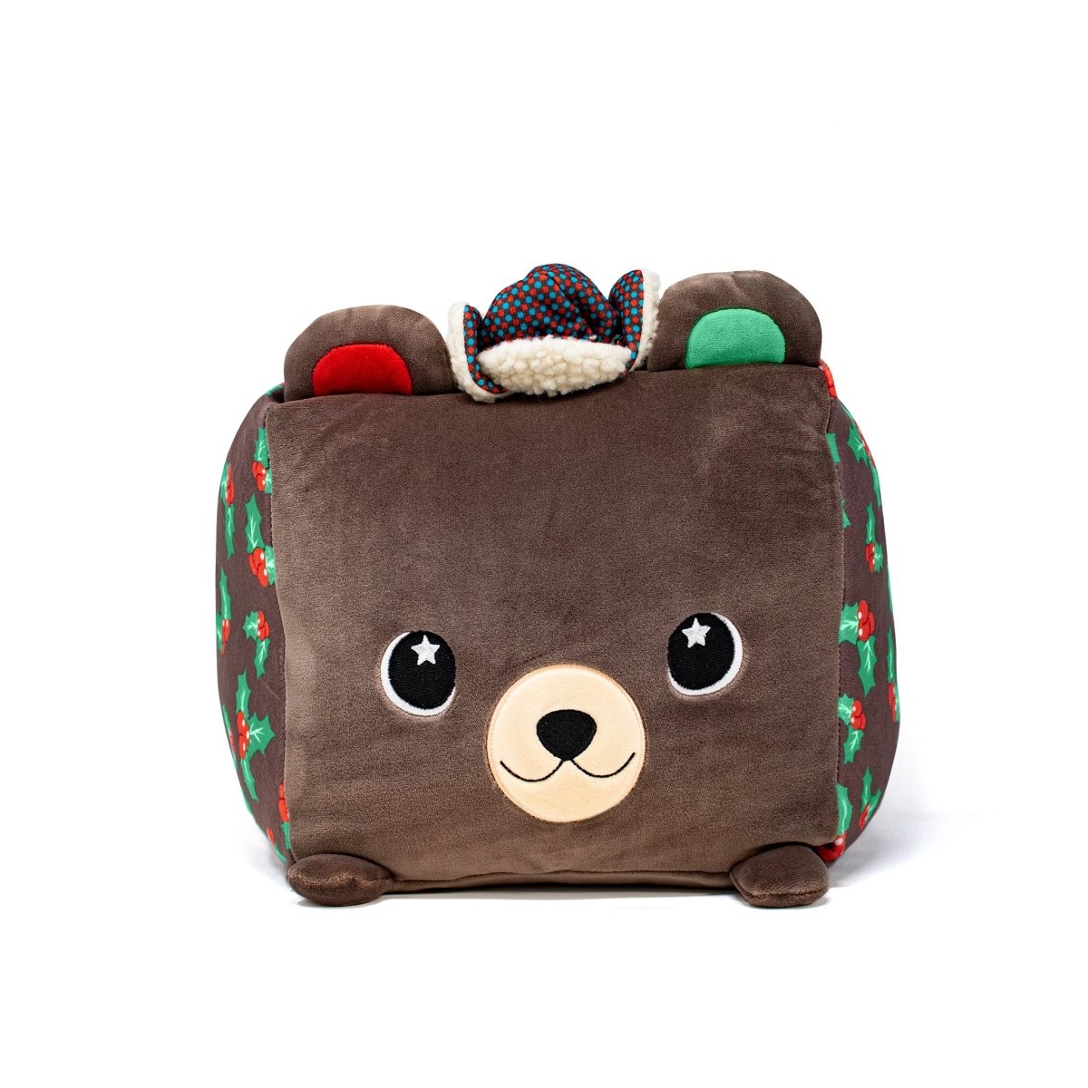 The Holly Plushie is a cube-shaped bear with a smiling face, large round eyes, small round ears, and festive designs like holly and red accents. It wears a multicolored patterned cowboy hat and is perfect for cozy cuddles.