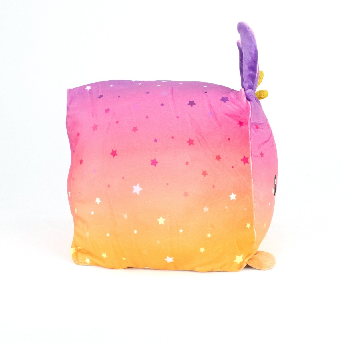 Jinx the Jackalope is a square, machine-washable pillow with a pink-to-yellow gradient, white and yellow stars, and purple/yellow bunny-like ears—perfect for fans of soft plush toys.