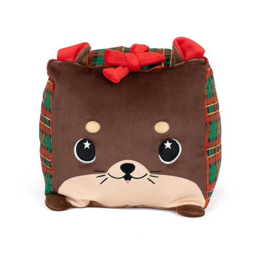 Joy the Otter is a cute, square stuffed plushie with a smiling face, round eyes, small ears, plaid green and red sides, and a red bow on top—perfect for cuddling.