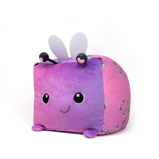 Introducing the Lovebug the Bee Plushie: a charming cube-shaped toy with a purple front, pink sides, a smiling face with starry eyes, and cute antennae. It features white wings, small legs, and bee patterns on its sidesโperfect for Valentine's Day!.