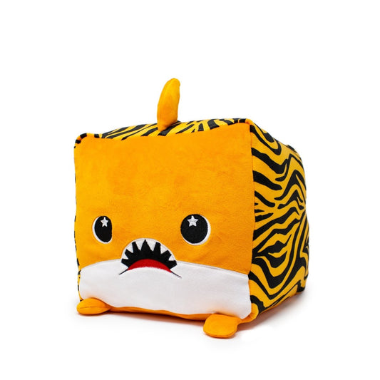 Mac the Tiger Shark Plushie is a soft, cubic plush toy with tiger print sides, an orange fin on top, and a cute face featuring big eyes and a small mouth with teeth. It has stubby orange and white legs at the bottom.