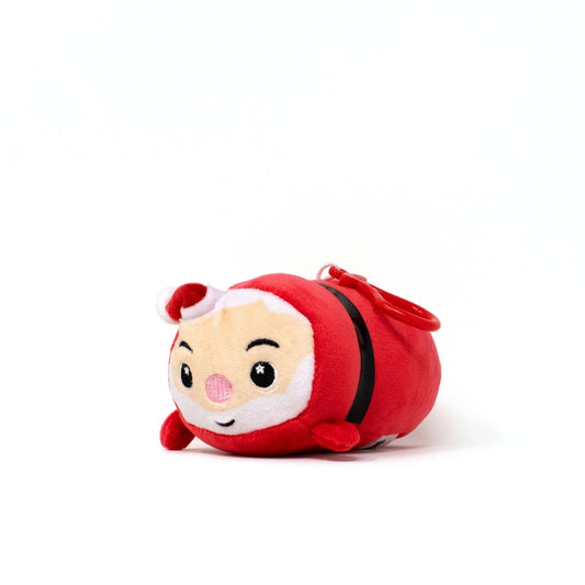 The Santa Clip-On is a small, round Christmas plushie resembling Santa Claus, featuring a red outfit, white trim, pink nose, and smiling face. It’s shown lying on its side against a white background.
