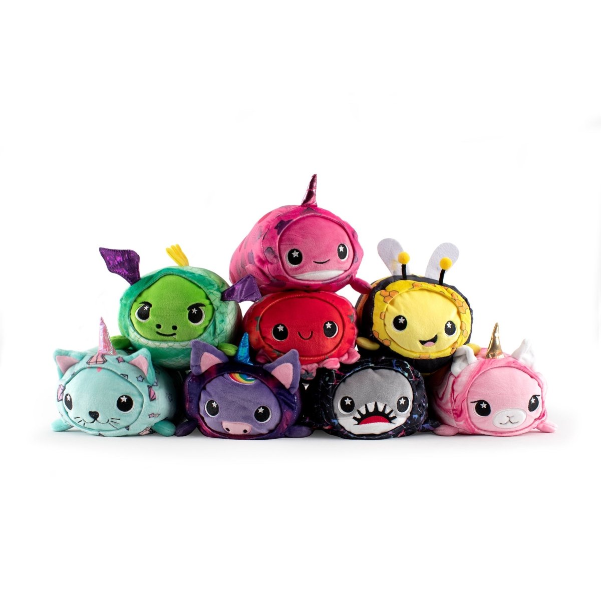 The Vee Slumber Plushie collection features colorful, round toys stacked in a pyramid. Each soft and squishy plush resembles a unique animal or creature like a unicorn, bee, shark, and dragon, complete with large eyes and smiling faces against a white backdrop.