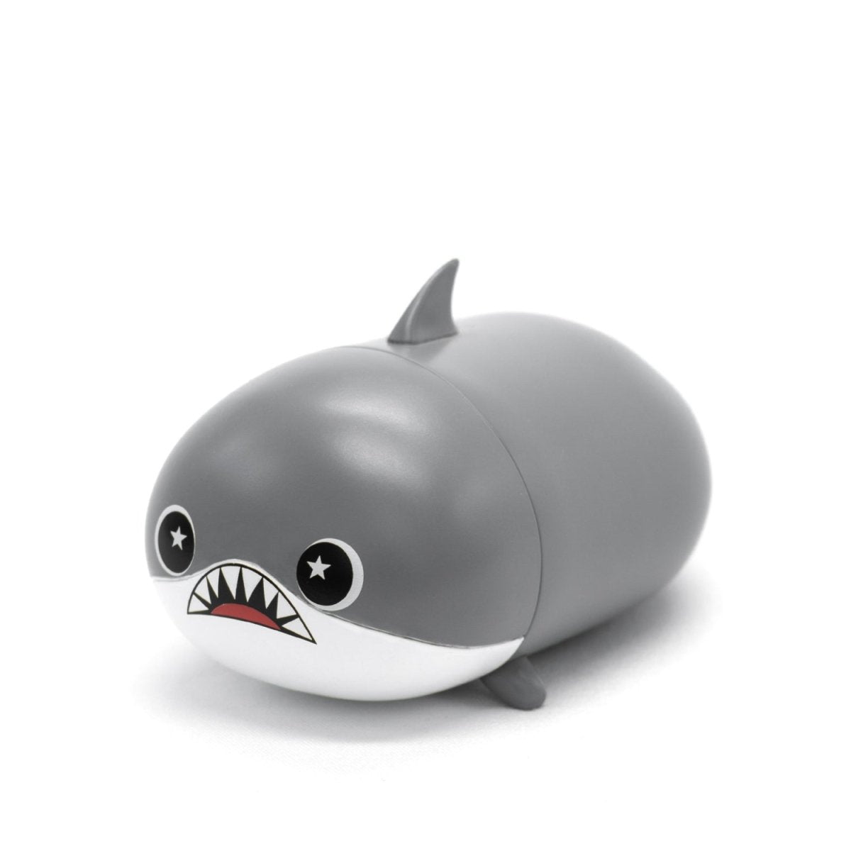The Crush the Shark Vinyl Collectible Figurine features a cute, cartoon-style design with a round body, starry eyes, and a wide grin. This collectible has a grey finish with a white belly and includes a small dorsal fin on its back.