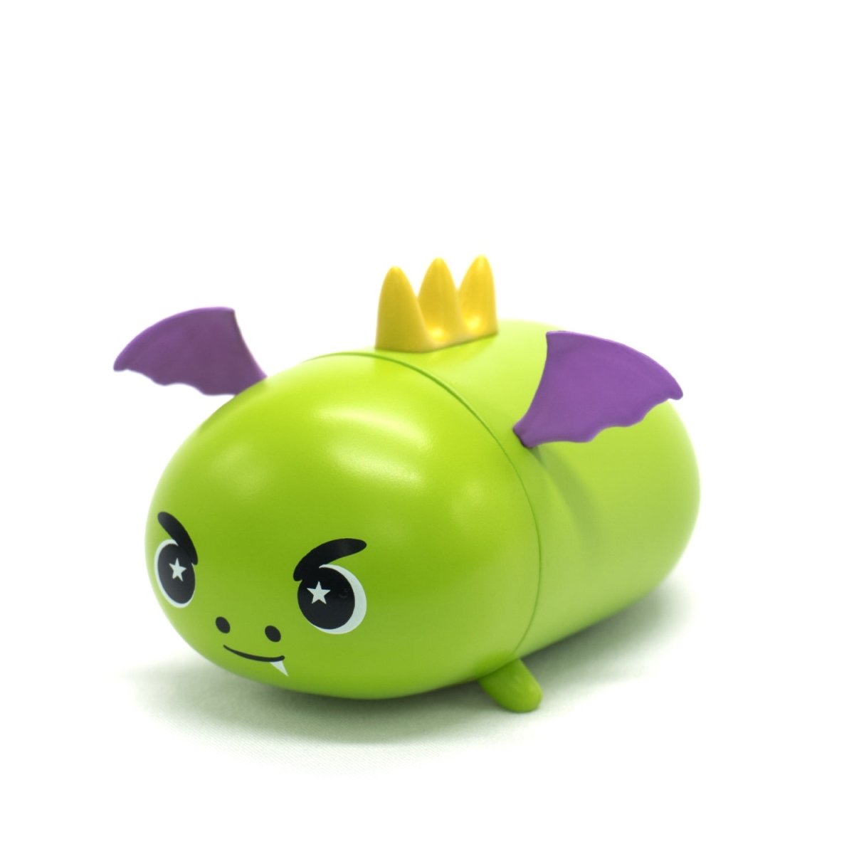 A small, green Drac the Dragon Vinyl Collectible Figurine with black eyes, a mischievous smile, purple bat wings, and a yellow crown on its head is shown against a plain white background.