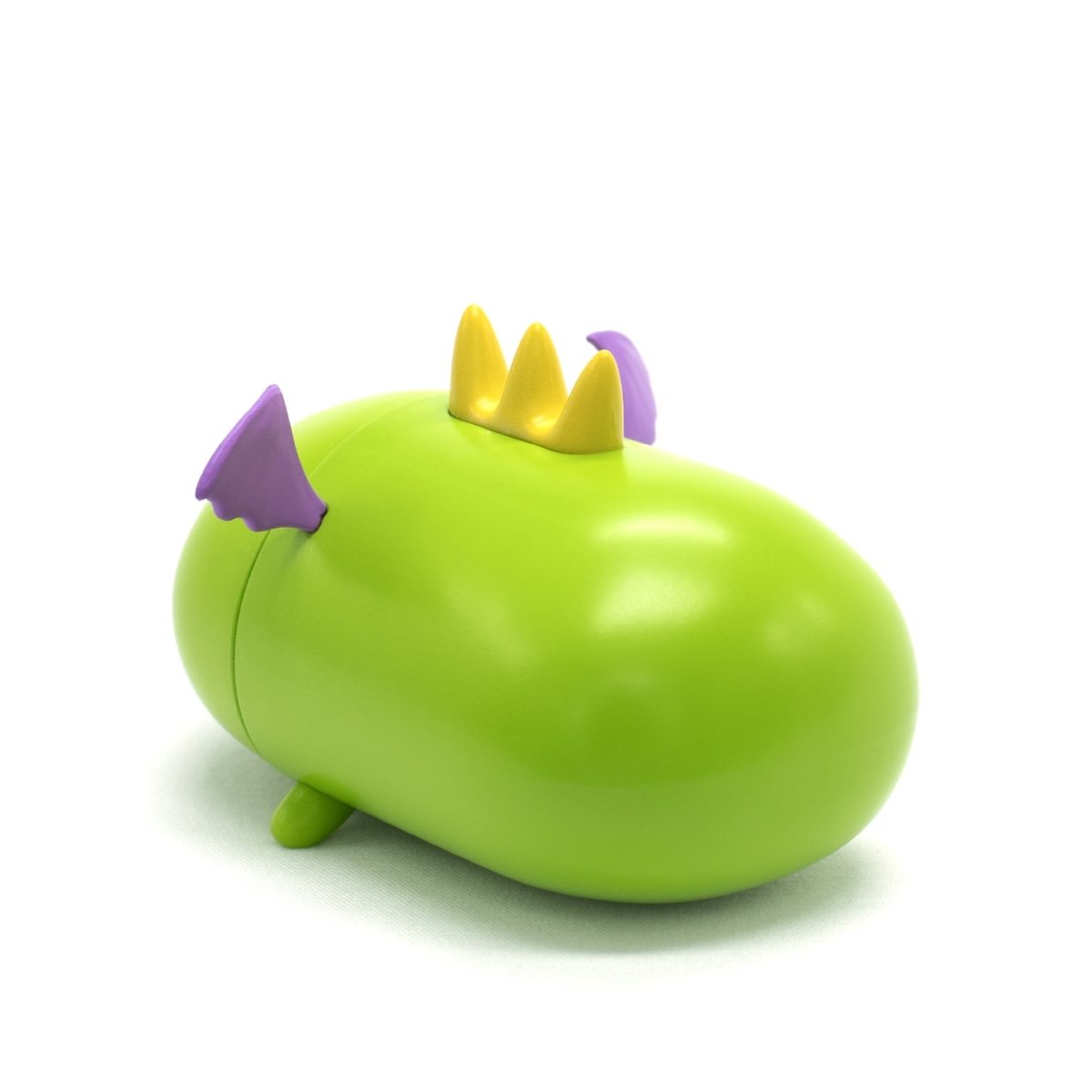 A smooth, green Drac the Dragon Vinyl Collectible Figurine with small yellow horns, purple bat-like wings, and two tiny feet is displayed on a white background.