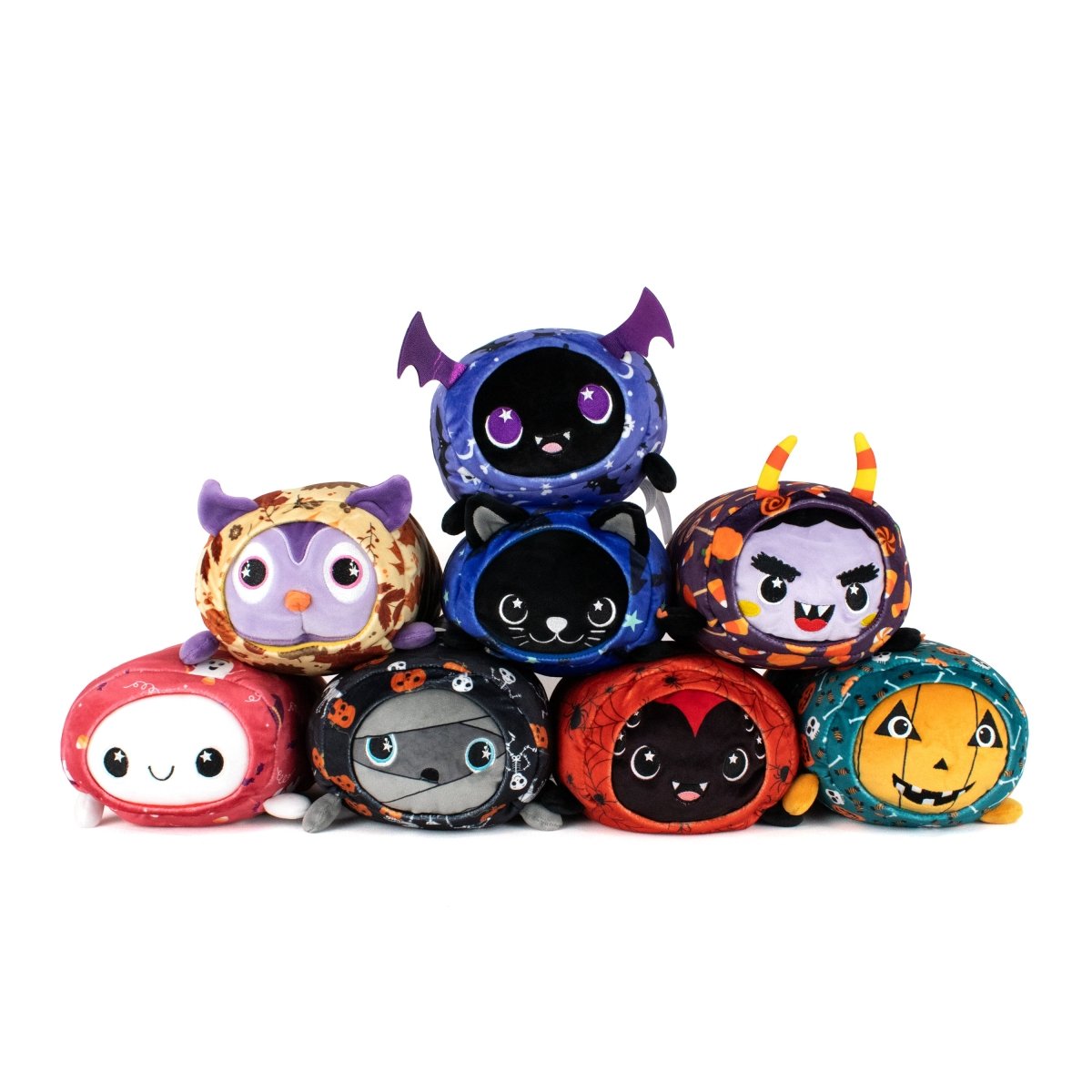 A pyramid stack of eight Fang Spooky Slumber Plushies—ultra-soft, round plushies featuring Halloween-themed designs like a vampire bat, pumpkin, devil, werewolf, witch, cat, and a smiling ghost.