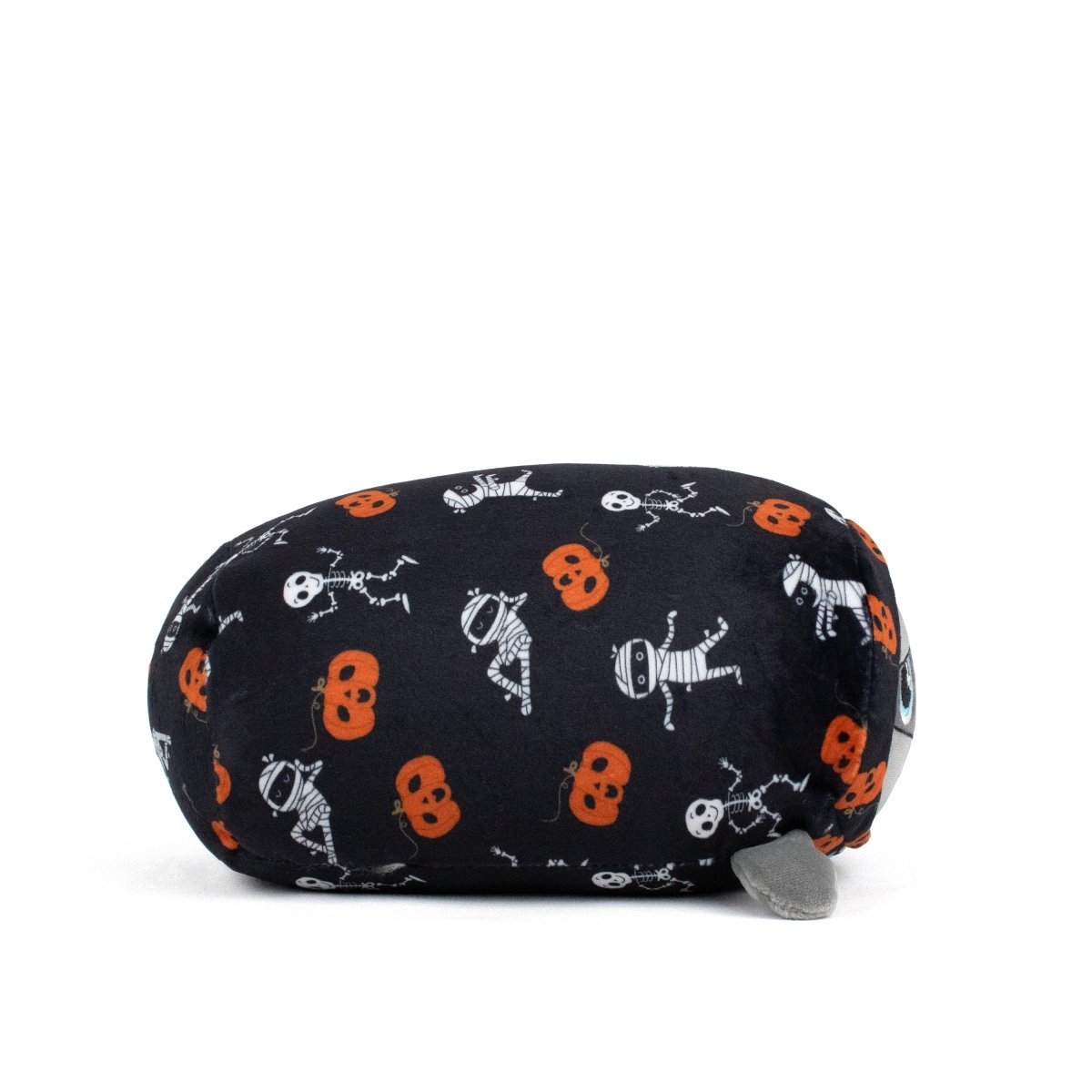 The Nile Spooky Slumber Plushie is a cat-shaped stuffed toy made from ultra-soft, machine-washable fabric. It features black fabric with orange pumpkins, skeletons, and mummies, plus a gray tail and blue eyes for extra charm.