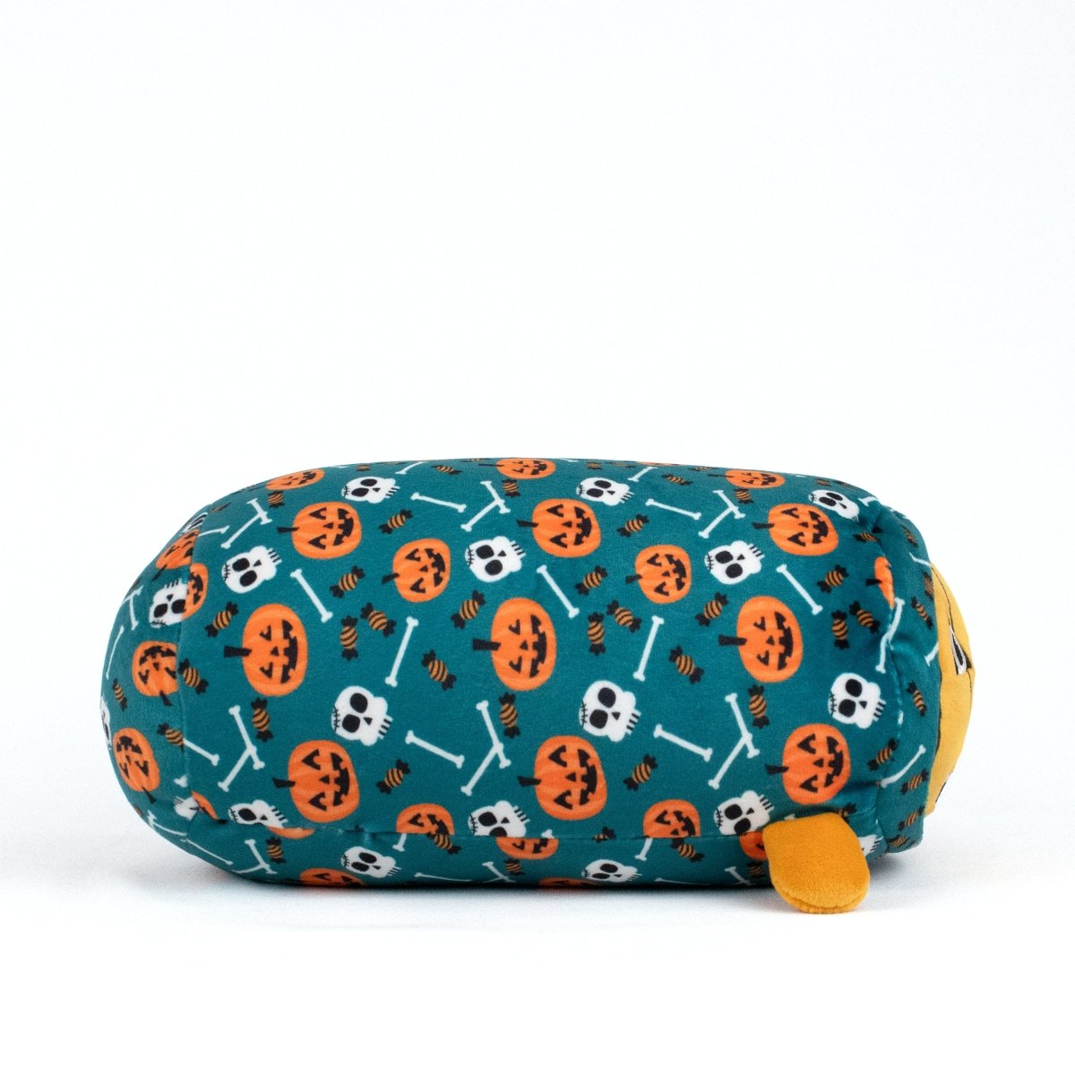 The Vincent Spooky Slumber Plushie is a cylindrical, ultra-soft, machine-washable plush with blue fabric, orange jack-o'-lanterns, white skulls and bones, small yellow feet, and a partially visible yellow face on one end.