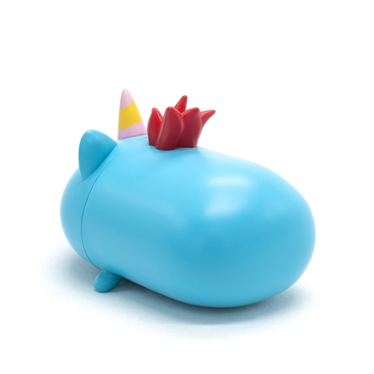 A small, smooth, blue toy with a striped horn, two ears, tiny legs, and a red spiky crest on its back is Sparkle the Unicorn Vinyl Collectible Figurine, shown on a white background.