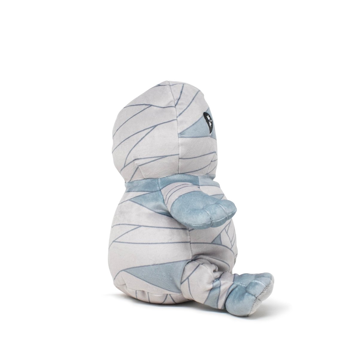 Nile the Mummy Plushie Starlight Buddy is a soft stuffed toy with simple black eyes and small limbs, wrapped in light gray fabric with darker gray bandage lines, sitting sideways against a plain white background.