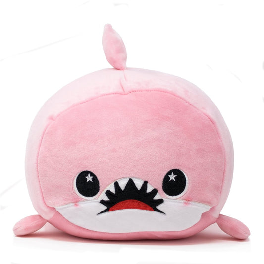 Nibbler the Pink Shark Plushie is an adorable, round figure with a small dorsal fin, wide dark eyes featuring star-shaped highlights, and a friendly open mouth with white teeth. It has a soft white belly on its cuddly body, set against a plain white background.