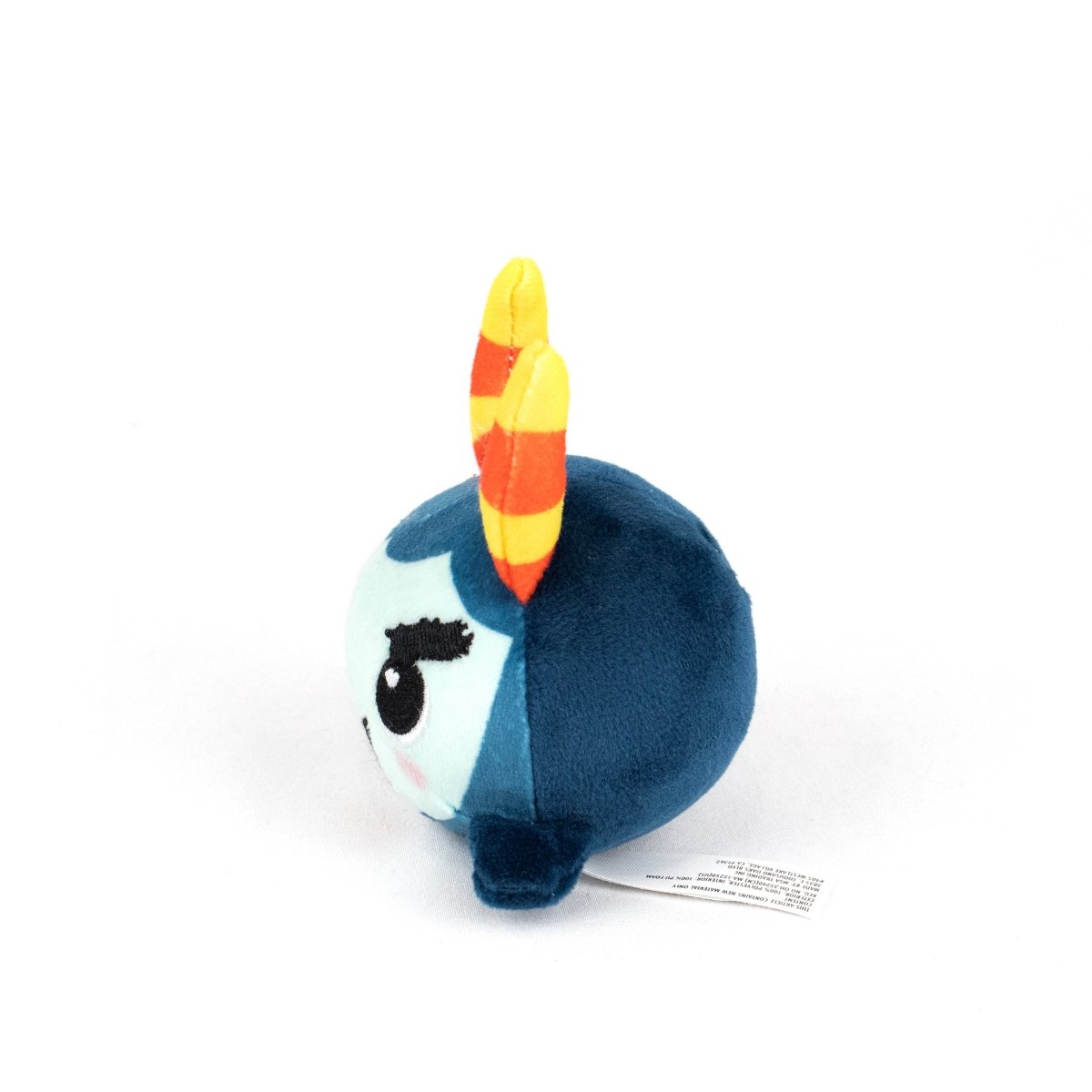 The Spike Spooky Plushy Skwishy is a round, blue plush toy with a light blue face, black embroidered eyelashes, pink cheeks, and orange-yellow striped horns on top, shown sitting on a white background.