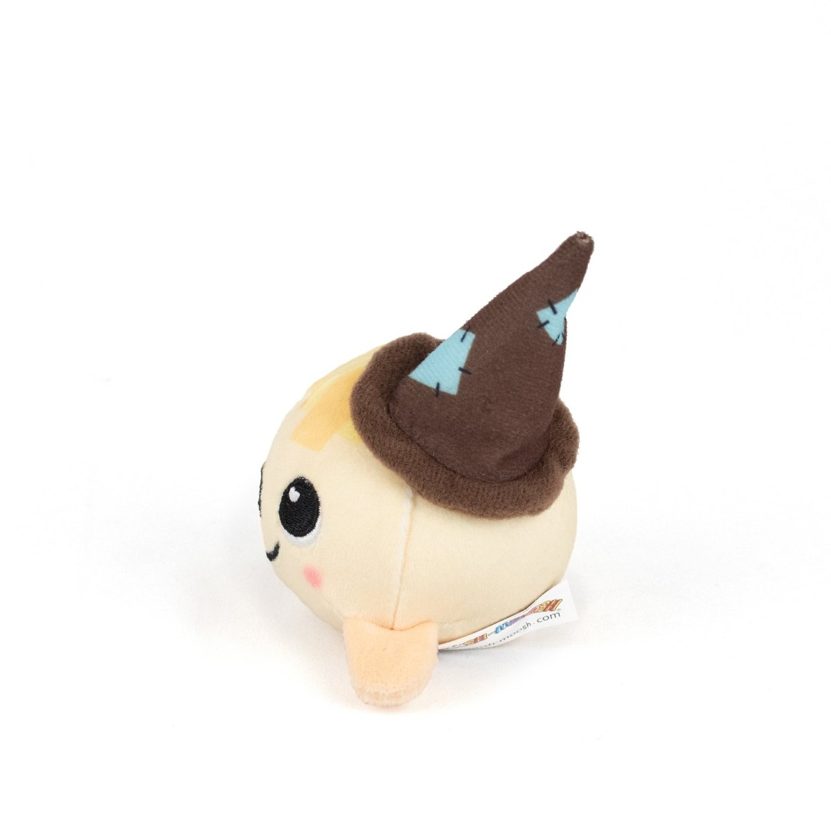 The Gretel Spooky Plushy Skwishy is a small, round plush toy with a beige body, light brown cheeks, a smiling face, and a brown pointed hat with blue patches. Shown on a white background.