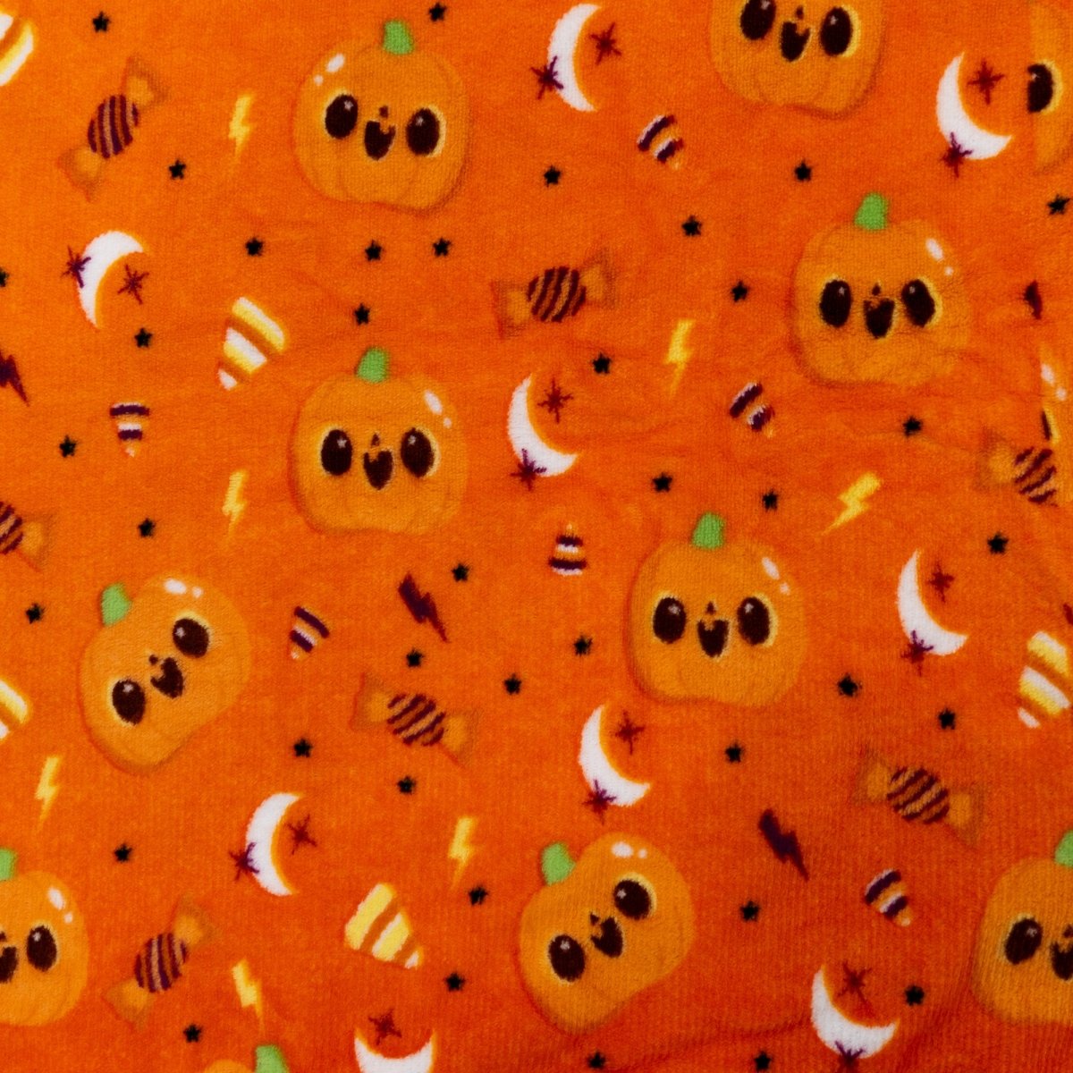 The Vincent the Pumpkin Hooded Blanket features orange fabric with smiling cartoon pumpkins, candy corn, candies, moons, stars, and lightning bolts—making it the perfect cozy Halloween kids’ blanket for festive nights.