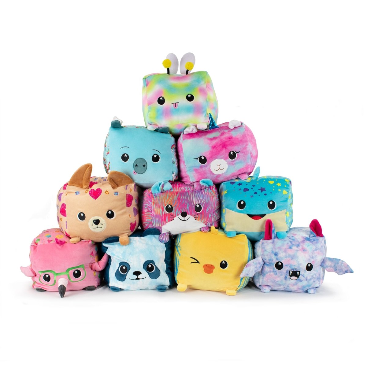 A pyramid of soft, cube-shaped stuffed animals displays vibrant designs, featuring Lyra the Bat Plushie alongside a bee, dog, and pig. Each plush boasts unique patterns and details like glasses, wings, and spots on a white background.