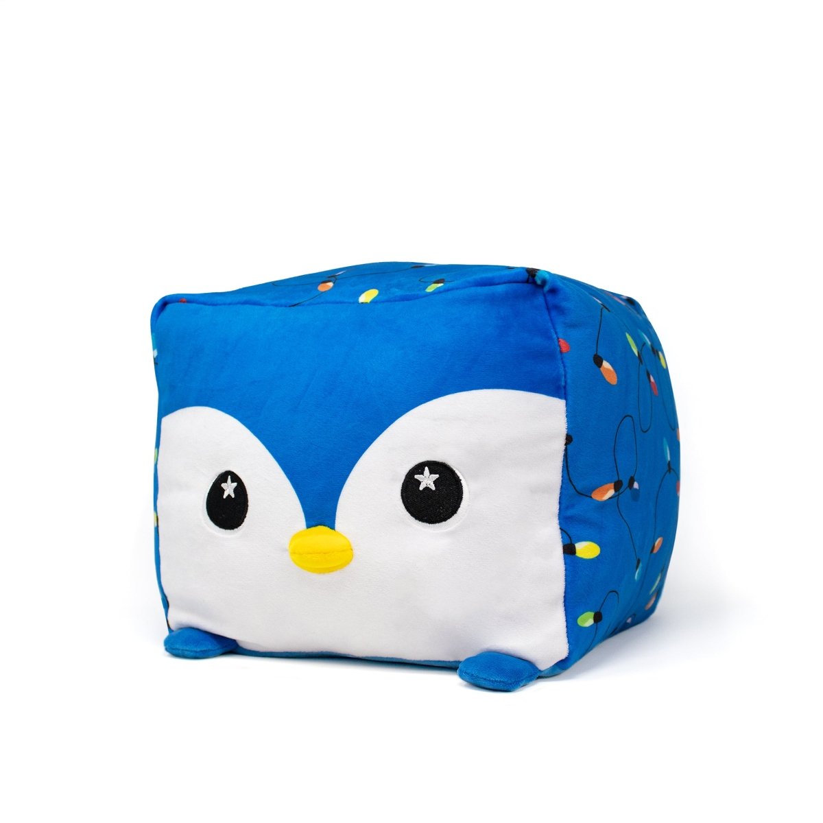 The Tanzy Plushie is a blue, cube-shaped Moosh-Moosh Squared2 holiday plush featuring a penguin face with a yellow beak, white cheeks, and colorful holiday lights on its sides, shown on a white background.
