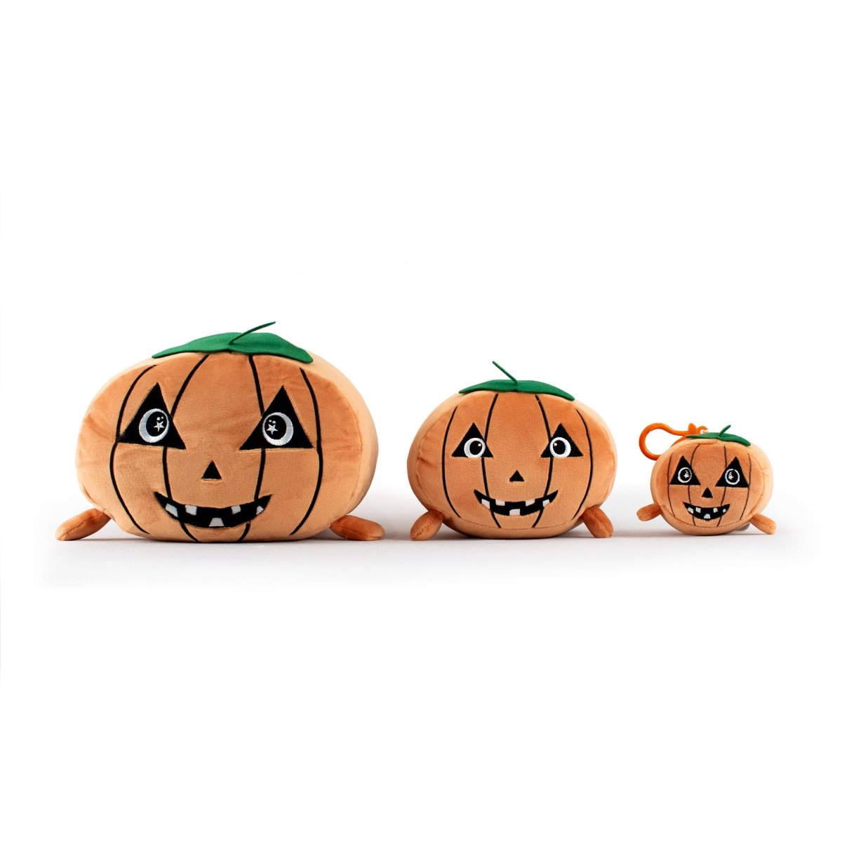 Three Vincent the Pumpkin Plushies, featuring stitched green tops and cheerful jack-o’-lantern faces, are lined up from largest to smallest on a white background. Each plushie is soft, cuddly, and cartoonish.