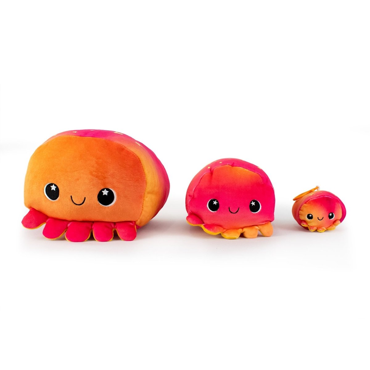 Three Dawn the Octopus Plushies in different sizes, each a soft stuffed toy with a gradient of orange and pink and smiling faces, are lined up in a row against a white background.