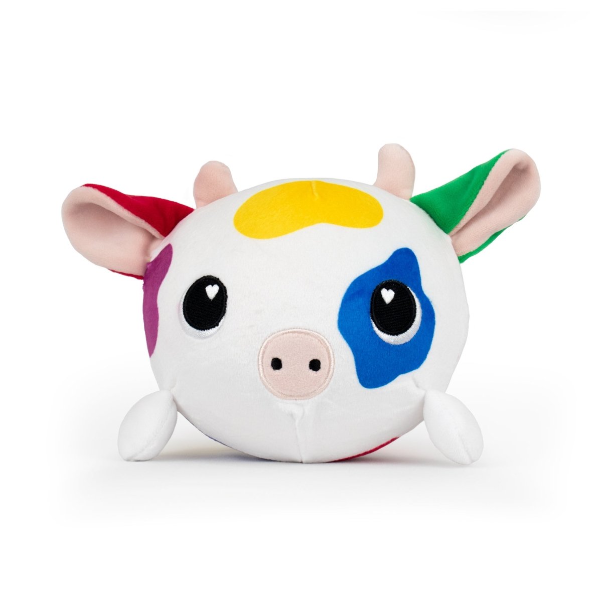 The Jumbo Plushy Skwishy Clara is a round plush cow toy featuring a white body with colorful patches. It has big black eyes with heart-shaped reflections, small horns, ears, and four stubby legs set against a plain white background.