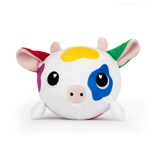 The Jumbo Plushy Skwishy Clara is a round plush cow toy featuring a white body with colorful patches. It has big black eyes with heart-shaped reflections, small horns, ears, and four stubby legs set against a plain white background.