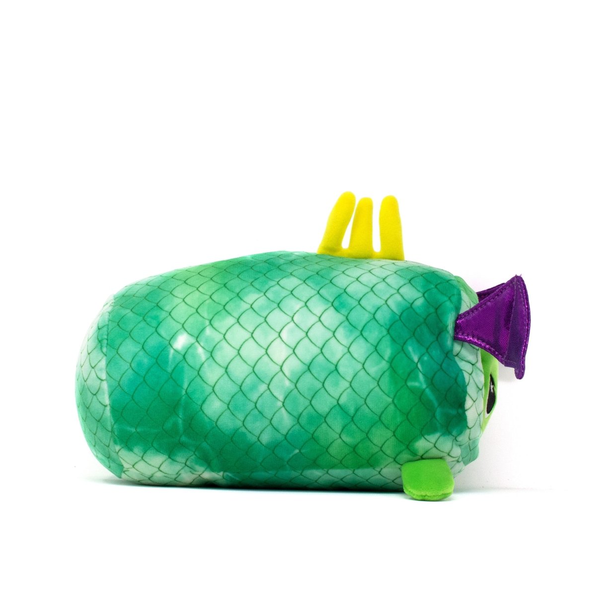 The Drac Slumber Plushie is a cute plush resembling a green fish with scaled patterns, purple fins, and yellow dorsal fins. This soft toy has a round cylindrical shape and lies on its side against a white background.