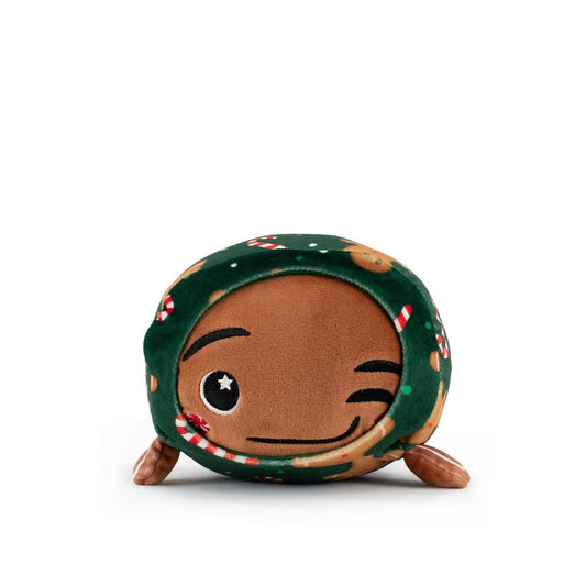 Gingersnaps the Gingerbread Slumber is a cuddly plush with a brown winking face, smiling expression, green fabric covered in gingerbread men and candy canes, and two small brown legs—ideal for holiday plushie lovers.