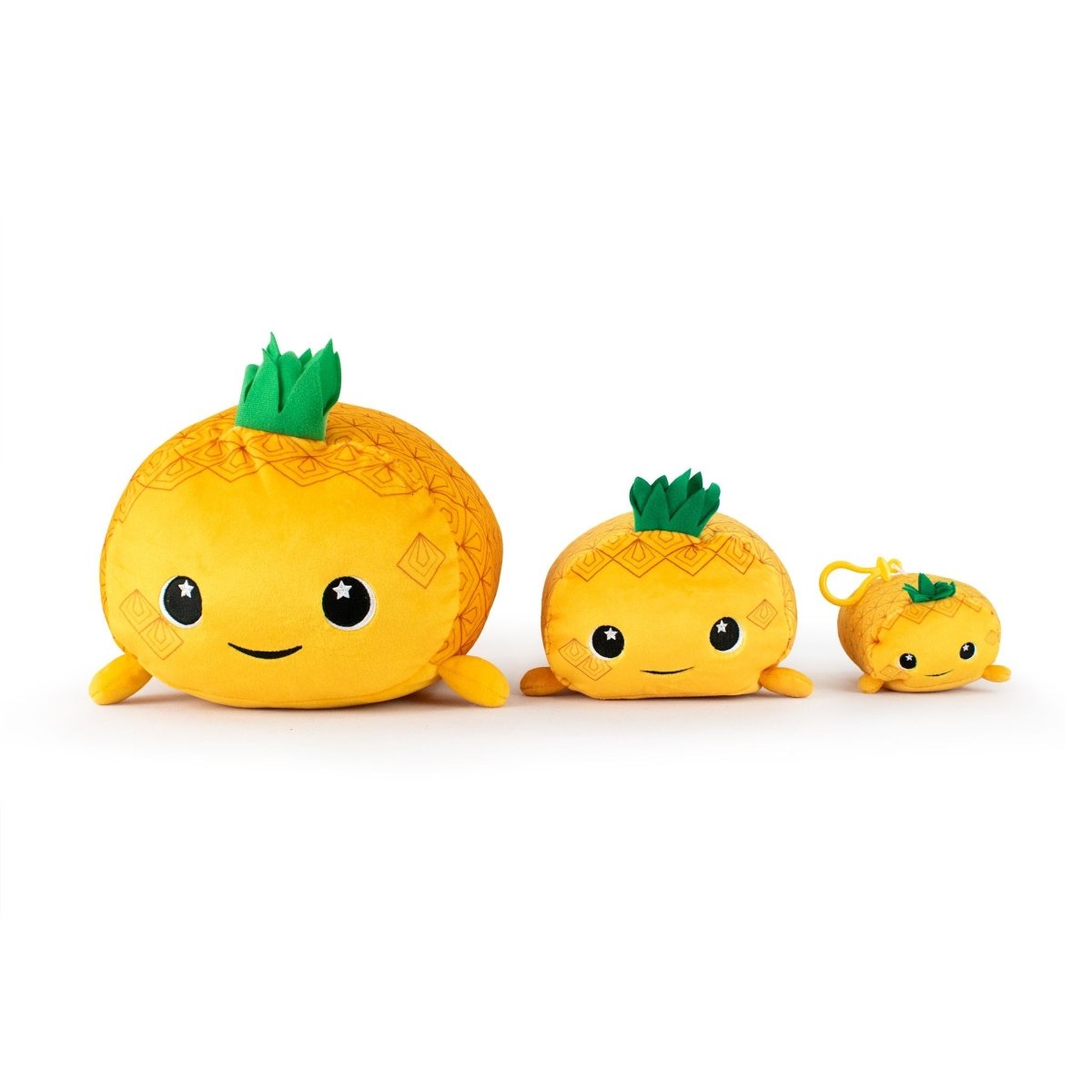 Three Ana the Pineapple Plushies, soft and squeezable, line up by size from right to left. With smiling faces, small arms and legs, and green leafy tops, they are irresistibly cute and friendly. They're also machine washable for easy care!.