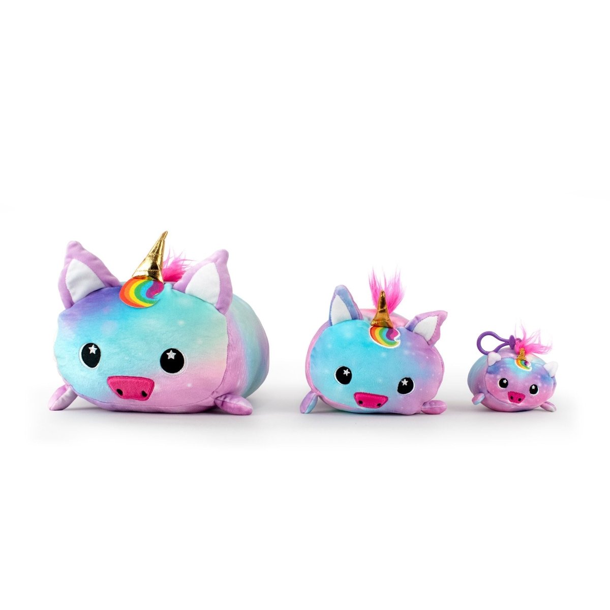 Nebula the Unicorn plushie set includes three soft, stuffed toys in pastel rainbow colors with big eyes. The largest features galaxy-colored fur and a golden horn, the medium one has a rainbow horn, and the smallest includes a hanging loop. All have pink snouts and ears.