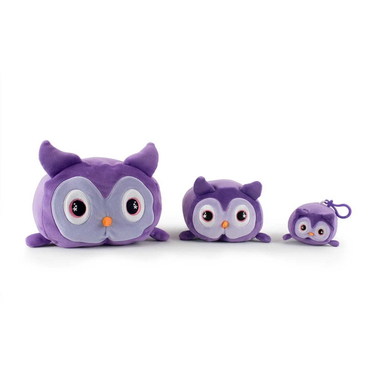 Three adorable purple plush owls with large eyes and small orange beaks are lined up on a soft white background, arranged from largest to smallest. The smallest owl, named Archie the Owl Clip-On, features a keychain for use as a charming accessory.