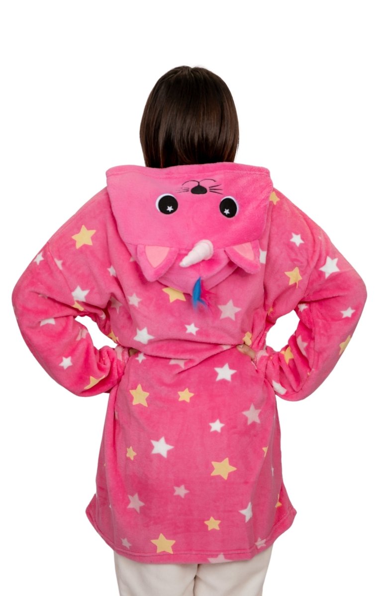 A person with brown hair is shown from the back wearing a whimsical Caticorn Hooded Blanket in bright pink with colorful star patterns. The soft fleece robe features a hood with cat ears, eyes, and a nose, and the individual stands with hands on hips.
