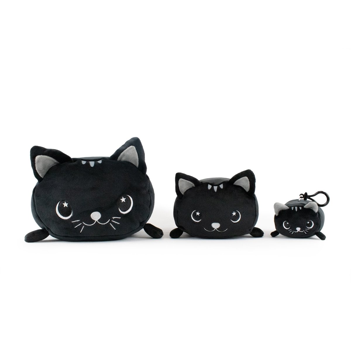 Three plushies shaped like black cats are arranged by size: a large and medium one with wide, soft bodies, and Fortune the Cat Clip-On as the smallest. All feature pointy ears and cute facial expressions.