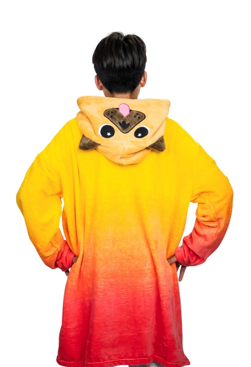A person stands with hands on hips, wearing the Pug Hooded Blanket—a cozy red and yellow ombre fleece with a cute pug face and ears on the hood—seen from the back against a white background.