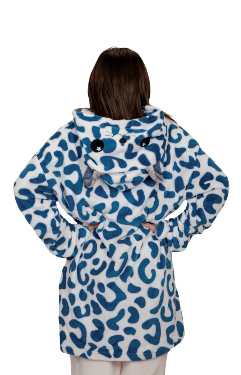 Someone stands with their back to the camera, wearing the Snowie the Leopard Hooded Blanket, featuring a blue and white design with playful animal ears and a face on the hood.