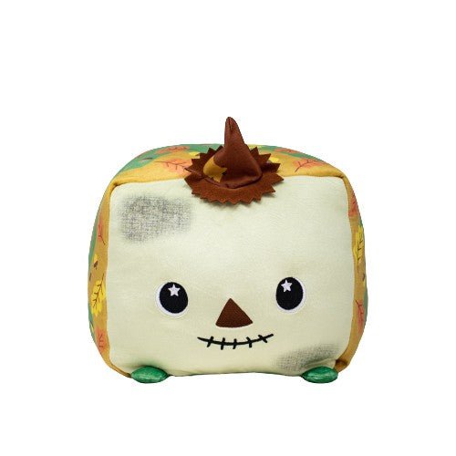 Tatters the Scarecrow is a soft, square plush toy featuring a stitched smile, black button-style eyes, a brown hat, and autumn leaf patterns—perfect as a cute fall companion.
