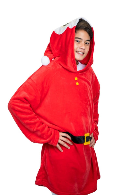 A child gleefully poses with hands on hips, wearing a Santa Hooded Blanket featuring a red oversized design, hood with white pom-pom, black belt graphics, and yellow buttons against a white backdrop.