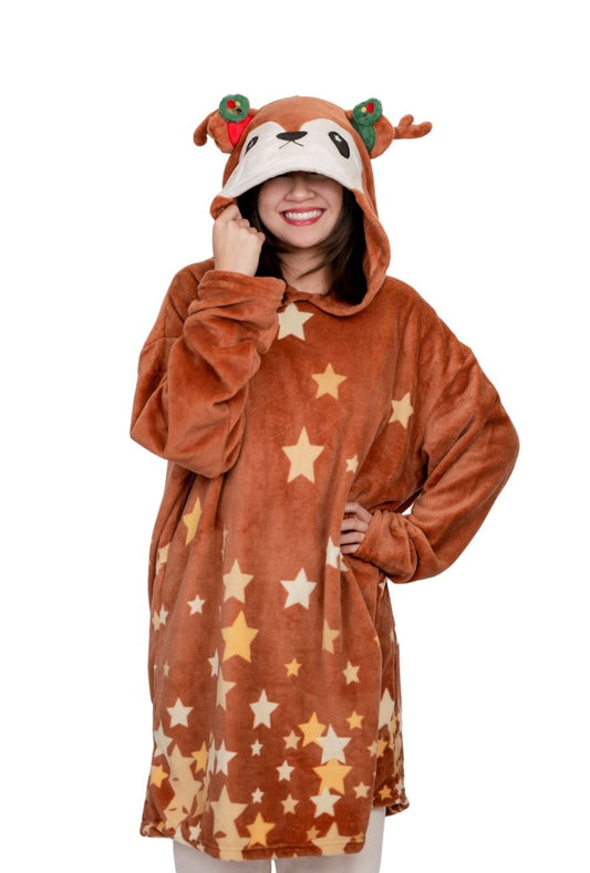 A person smiles in the Mitzy the Reindeer Hooded Blanket, featuring a reindeer face, antlers, red decorations, and star patterns. The hood is up against a plain white background for a festive holiday look.