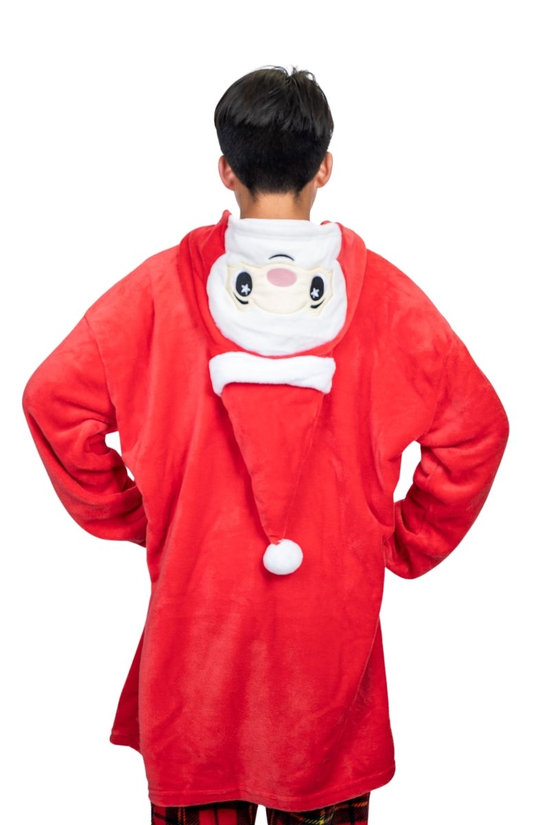 A person in a Santa Hooded Blanket, like a festive plush toy, stands with their back to the camera, hands on hips. The blanket features a cheerful Santa face on the hood, complete with a white pom-pom and festive details.