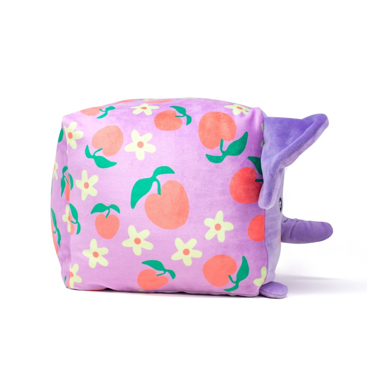 The Peach Squared Plushie is a cuddly, square-shaped toy with an elephant trunk, adorned with purple fabric featuring peaches and small flowers. Its soft purple ears are perfect for endless cuddling, and it’s conveniently machine washable against a plain white background.