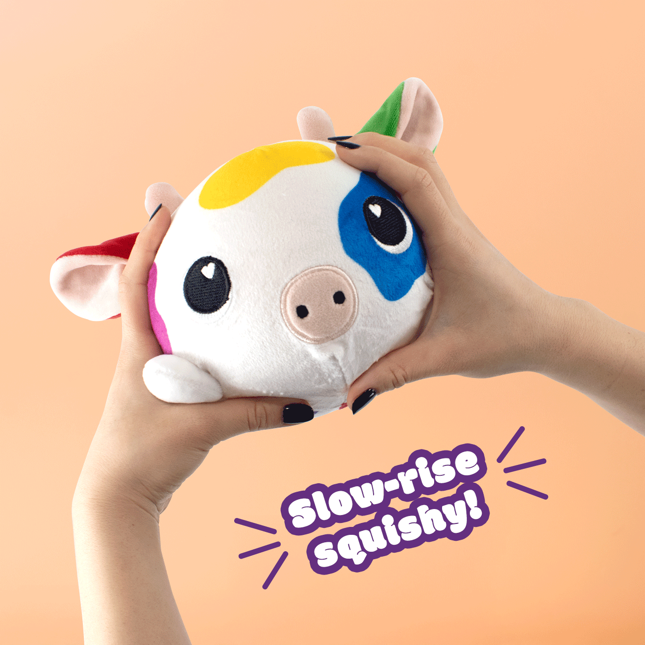 Hands squeezing a colorful cow-themed plush toy with pig-like features. Text reads "Slow-rise Squishy!" in purple with decorative lines. Background is a peachy orange.