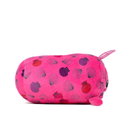 Introducing the Bubblegum Slumber Plushie: a bright pink, machine washable round pig shaped toy with small ears, tail, and a pattern of purple and red seashells. Featuring a smiling face and small black eyes, it's perfect as a soft pillow for cozy cuddles.