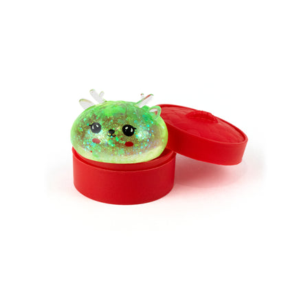 A glittery green Bubblegum’s Favorite Toy - Jr Reindeer Mystery Maltose Dumpling squishy toy sitting inside an open red container.