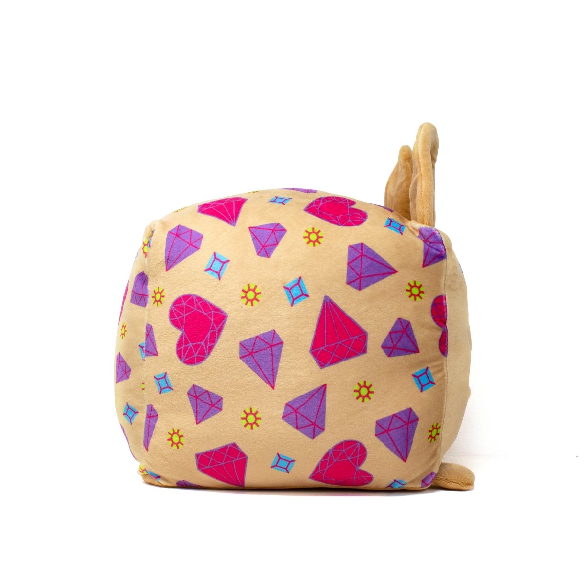 A charming plush toy, Bev the Chihuahua Plushie, displays vibrant geometric patterns with pink and purple diamonds, hearts, and suns on its soft brown body. It stands out vividly against a plain white background.